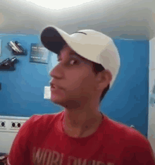 a man wearing a white hat and a red shirt is standing in a room .