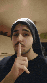 a man with a beard is making a shhh sign