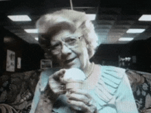 an elderly woman is holding an ice cream cone in her hand