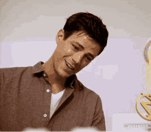 a man in a brown shirt is smiling and looking at a trophy .