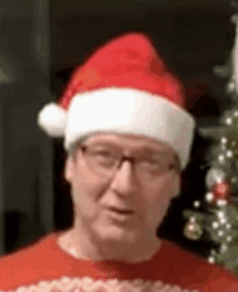 a close up of a man wearing a santa hat and glasses .