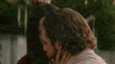 a man and a woman are hugging each other . the woman is touching the man 's face .