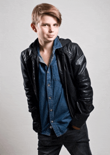 a young boy wearing a black leather jacket and a blue shirt