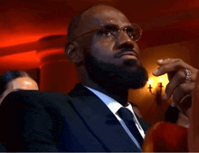 a man with a beard and glasses is sitting in a room .