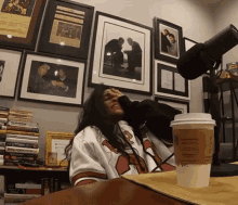 a woman sitting at a table with a cup of coffee that says starbucks on it