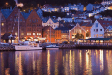 a row of boats are docked in a harbor with buildings in the background at night