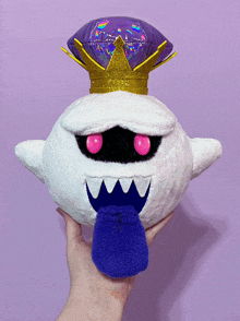 a person is holding a stuffed toy with a crown on it