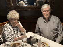 a man and a woman are sitting at a table with plates of food and glasses of water