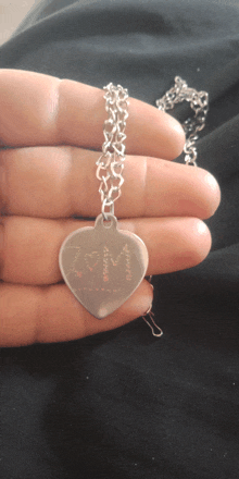 a person is holding a silver heart shaped necklace that says always