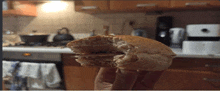 a person is holding a half eaten sandwich in front of a kitchen counter