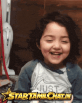 a little girl wearing a shirt that says just is smiling