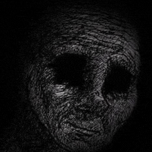 a black and white drawing of a person 's face with black eyes in the dark .