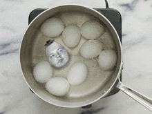 eggs are boiling in a pot with a man 's face in the middle