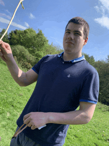 a man wearing a blue shirt with a lion on it holds a stick