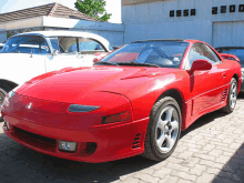 a red sports car is parked in front of a building that says ossa on it