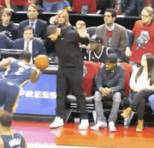 a man is standing on a basketball court holding a basketball in front of a crowd of people .