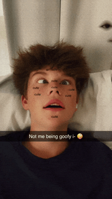 a young man laying on a bed with the word cute written on his face