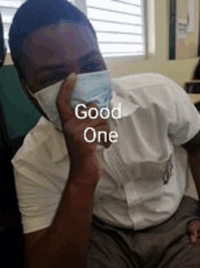 a young man wearing a face mask is sitting in a classroom and making a funny face .