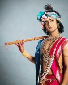 a man dressed as a krishna holds a flute over his shoulder