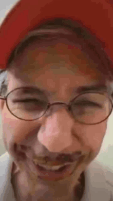 a close up of a person wearing glasses and a red hat .