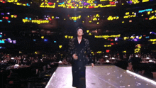 a man in a black jacket is dancing on a stage in front of a crowd of people