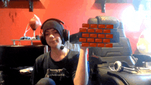 a man wearing headphones holds a brick wall in front of a chair that says xrocket