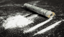 a roll of money laying on a pile of cocaine