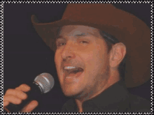 a man wearing a cowboy hat sings into a microphone