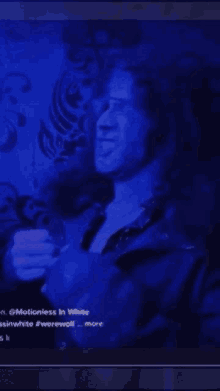 a man with long hair is smoking a cigarette in a blue room .