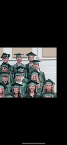 a group of graduates wearing green caps and gowns pose for a picture