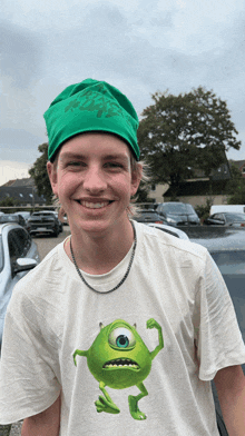 a young man wearing a green hat and a white shirt with mike from monsters inc on it