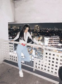 a woman standing on a balcony with a city in the background