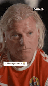 a man with blonde hair is wearing a red shirt that says canal + on the bottom