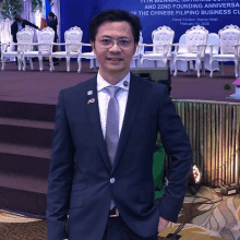 a man in a suit and tie stands in front of a sign that says fiesta pavilion manila hotel february 10th 2020