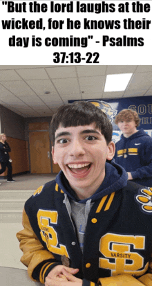 a boy wearing a varsity jacket laughs in front of a bible verse