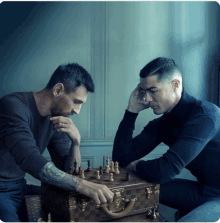 two men are playing a game of chess with a louis vuitton suitcase in the background