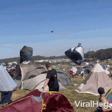 a man in a black shirt stands in front of a field of tents with the words viralhog written in the corner