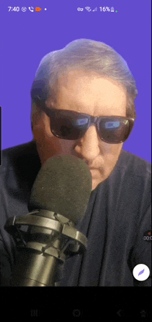 a man wearing sunglasses is talking into a microphone on a phone screen