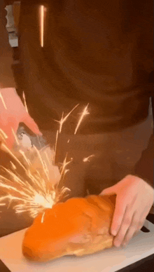 a person is cutting a piece of meat on a cutting board with sparks coming out of it