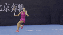 a woman in a pink dress holding a tennis racquet