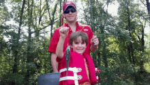 a man and a boy are standing next to each other holding fishing rods .