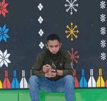 a man wearing a mask is sitting in front of a wall with snowflakes