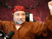 a man with antlers on his head is sitting in front of a microphone with his fist in the air