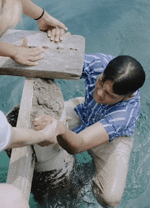 a man in a blue and white striped shirt is kneeling in a pool of water