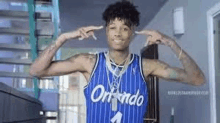 a young man wearing a blue striped basketball jersey is covering his ears with his hands .