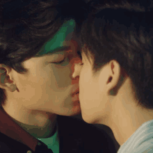 two men are kissing each other in front of a green light