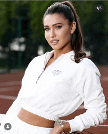 a woman wearing a white sweater with a tennis racquet on it