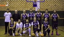 a group of men are posing for a picture on a basketball court with basketballs .