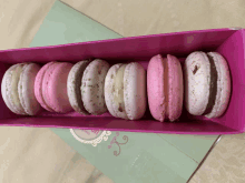 a row of pink and white macarons in a box