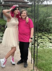 a woman in a white dress is posing for a picture with a boy in a pink shirt .